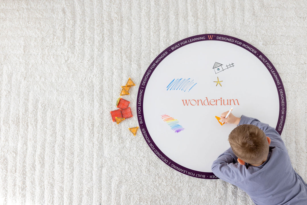 A child drawing freely on a Wonderium drawing station, with magnetic construction pieces beside it