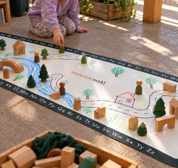 A child building with wooden blocks on a Wonderium learning mat