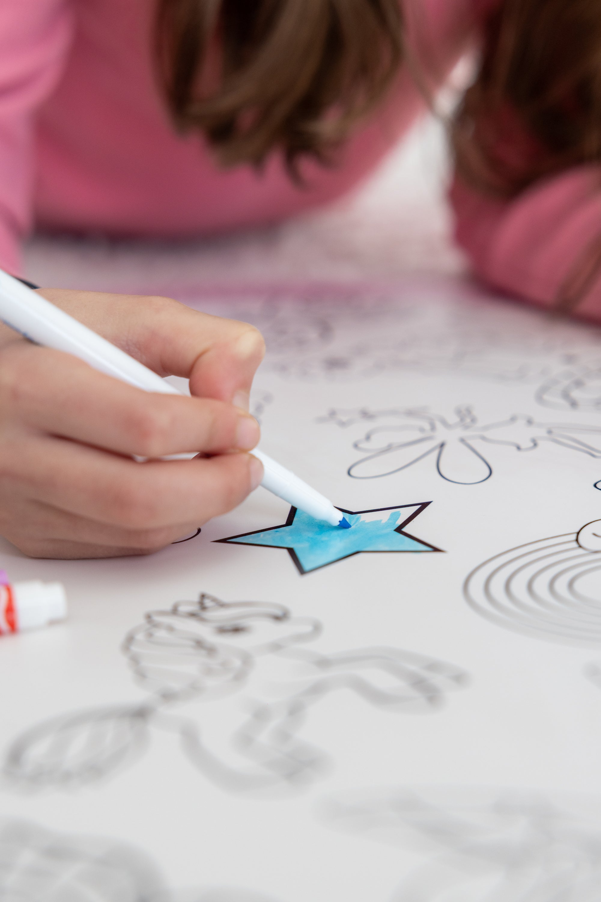 A child adding blue colour to a star on a Wonderium mat