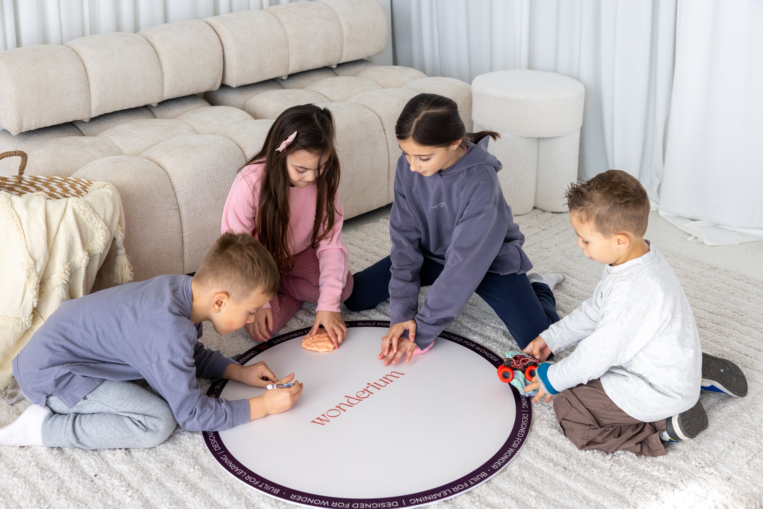 Four children drawing, playing with dough and exploring toys together on a Wonderium mat
